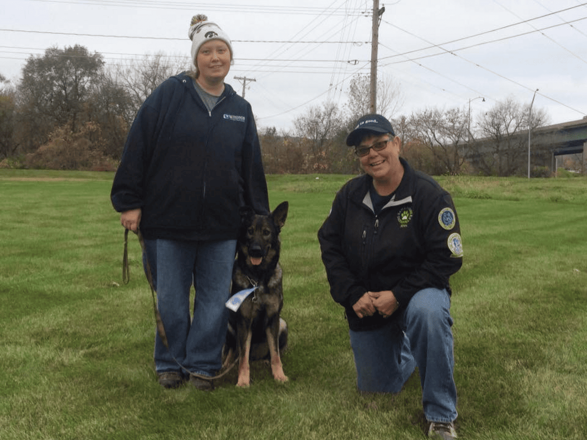 Two handlers posed with a trained dog